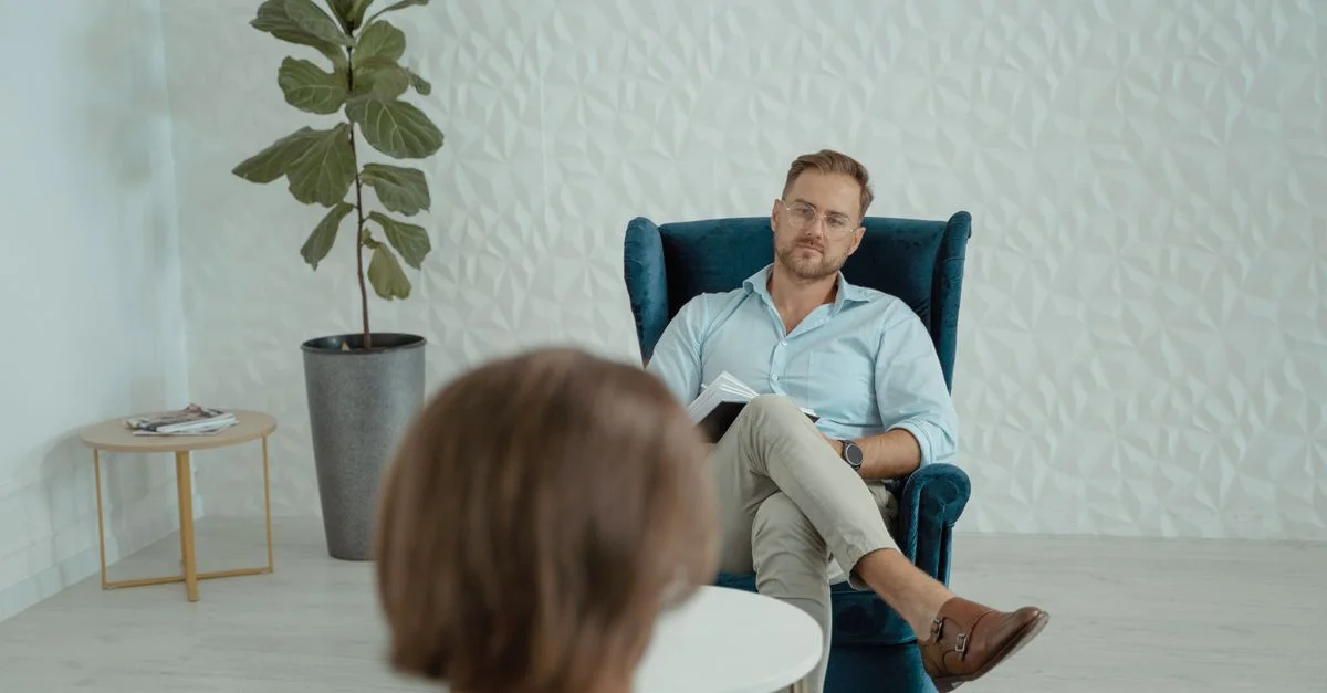 Une séance de counseling avec un homme assis dans un fauteuil confortable à l'intérieur.