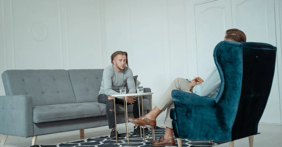 Deux hommes engagés dans une séance de thérapie dans un bureau moderne, discutant de la santé mentale.