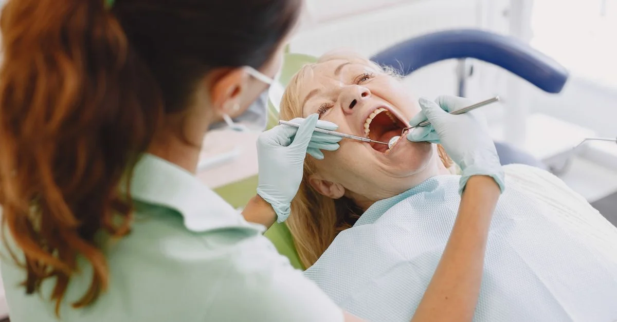 Une dentiste examine un patient dans une clinique dentaire, montrant des soins professionnels.