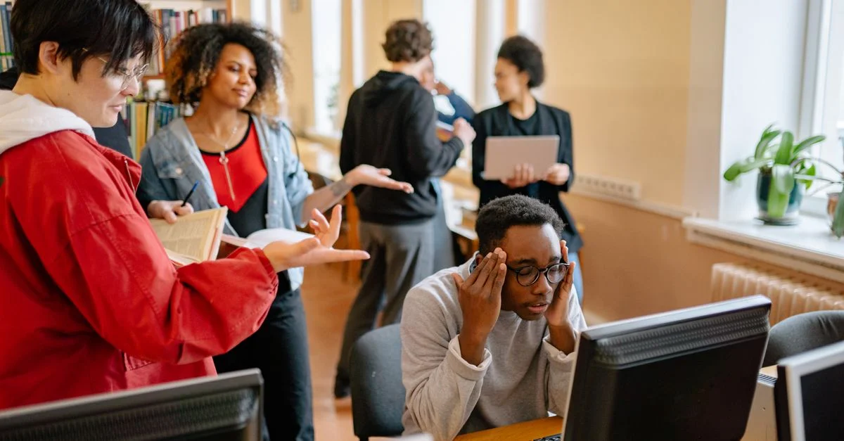 Un groupe d'étudiants divers engagés dans l'étude dans une bibliothèque avec des ordinateurs et des livres.
