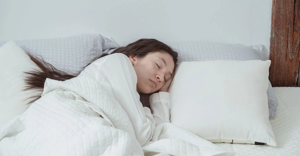 Une image sereine d'une femme profondément endormie dans une chambre confortable et lumineuse.
