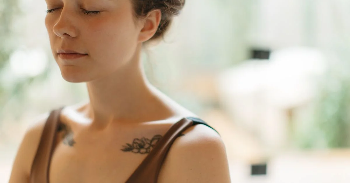 Femme les yeux fermés méditant à l'intérieur, symbolisant la tranquillité et la concentration.