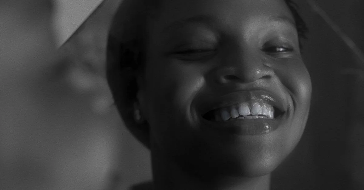 Portrait élégant en noir et blanc d'une femme souriante capturé en flou doux.