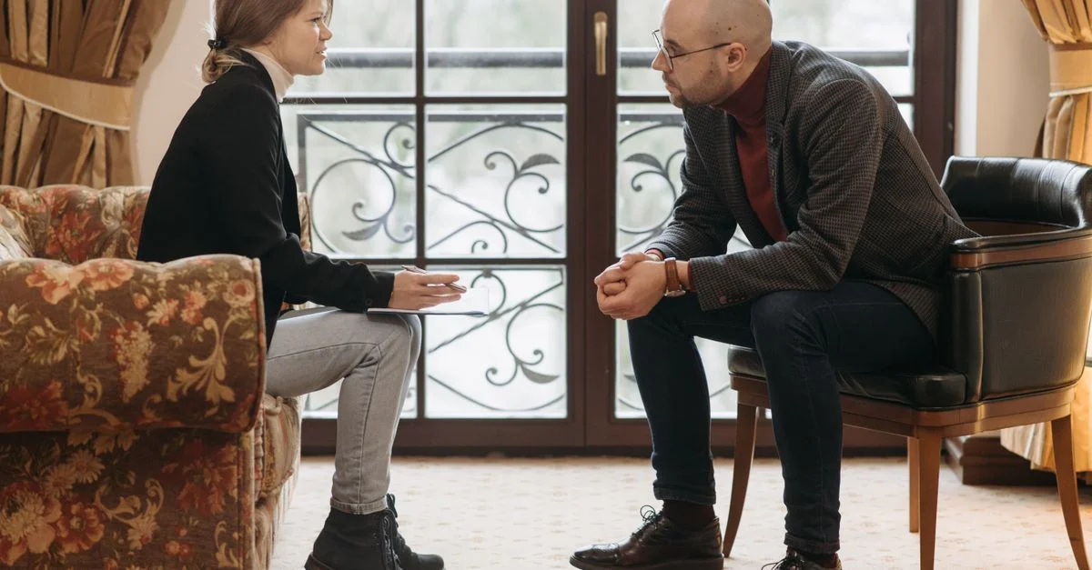 Une séance de thérapie stimulante avec un thérapeute et un client discutant dans une pièce confortable.