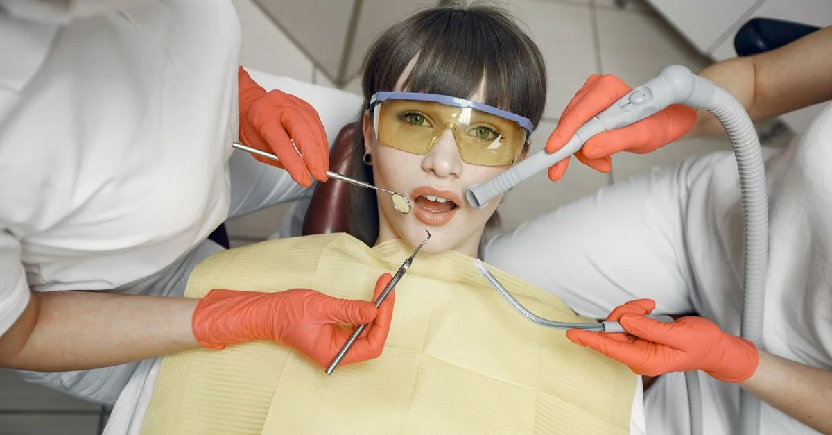 Dentiste effectuant un contrôle avec des équipements de protection et des outils dans une clinique.